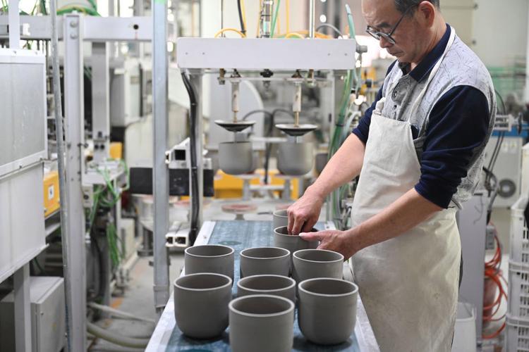 10月21日,在福建省泉州市德化县顺美陶瓷厂,工人操作机器制作陶瓷产品